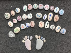 Big journeys begin with small steps, inspiration quote with stones