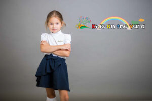 The girl, the schoolgirl, the second grader in a school skirt and white golfs poses on a gray